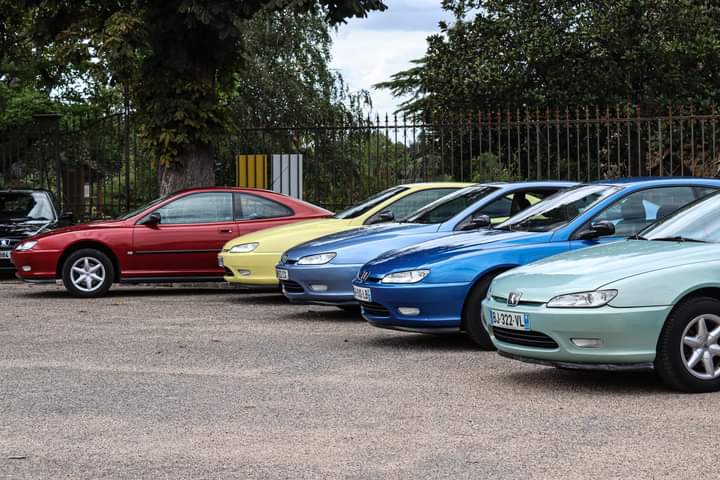 Rangée de 406 Coupé rouge, jaune, bleue et verte alignées le long d'une grille